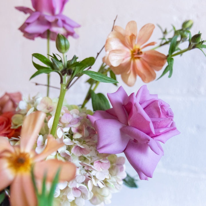 Colorful bouquet of flowers including pink, orange, and yellow flowers on a light background