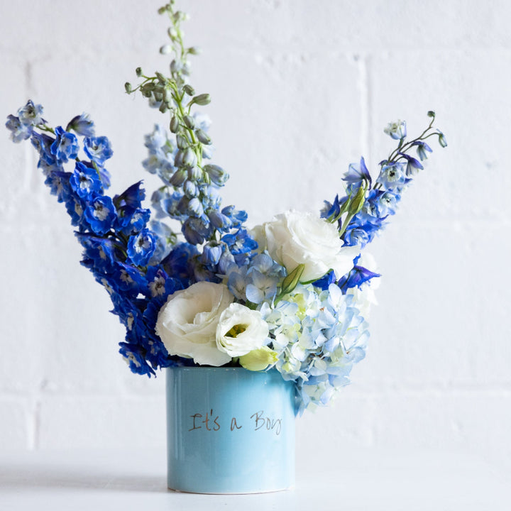 Floral arrangement in a blue container with 'It's a Boy' text on a white background