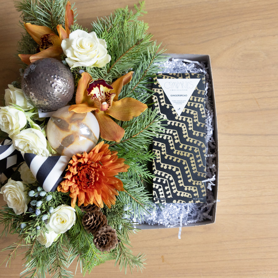 Decorative floral arrangement with ornaments and a patterned box on a wooden surface
