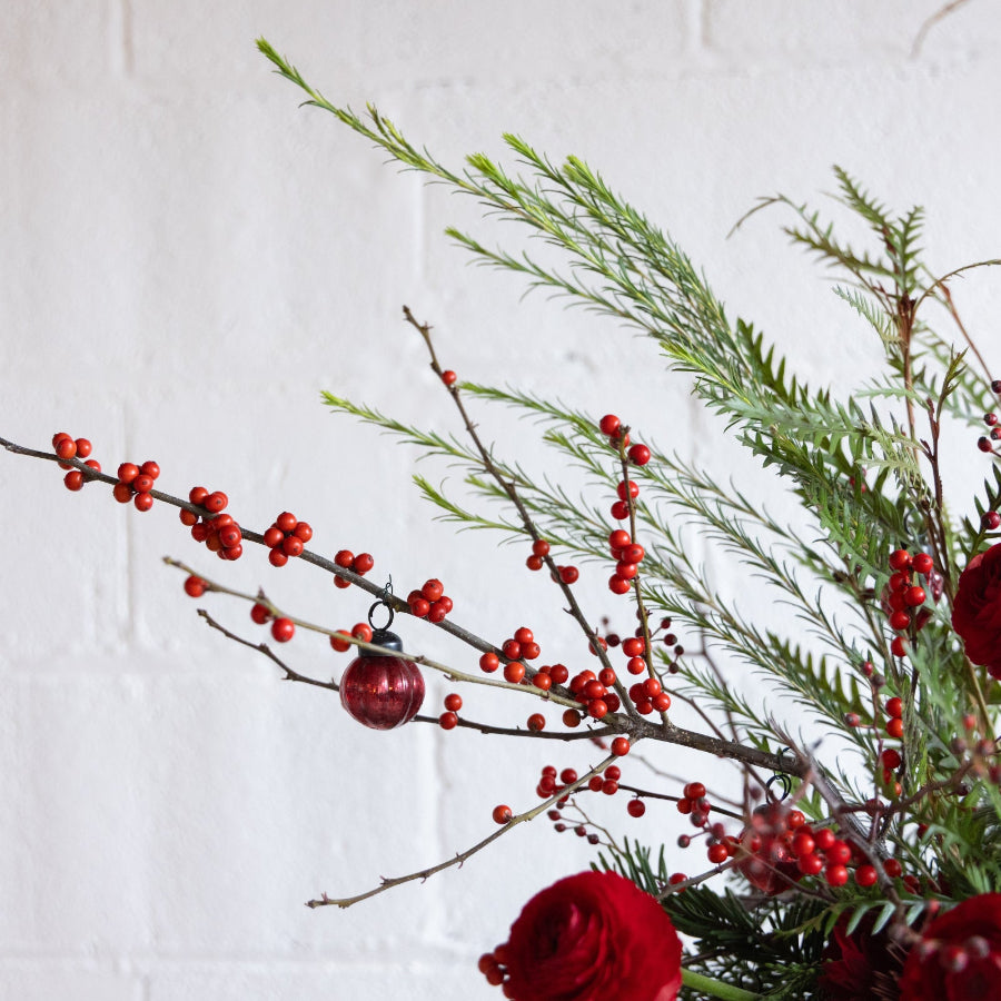 Decorative arrangement with red berries and a small ornament on a white background