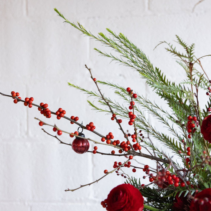 Decorative arrangement with red berries and a small ornament on a white background
