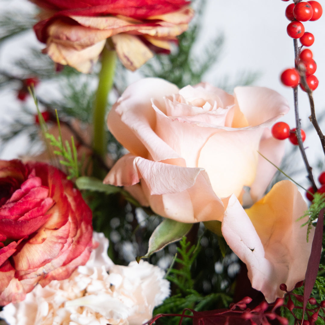 Close-up of a bouquet with pink roses, red flowers, and greenery.