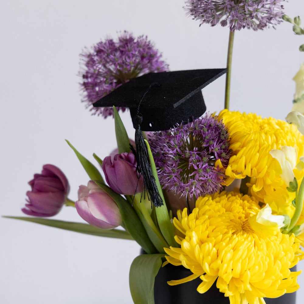 Bouquet of flowers with a black graduation cap on a white background