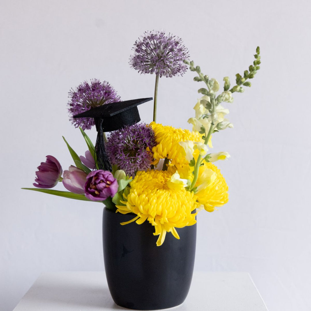 Black vase with yellow and purple flowers on a white background
