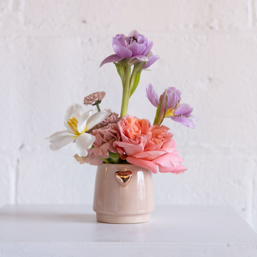 Small vase with colorful flowers on a white background