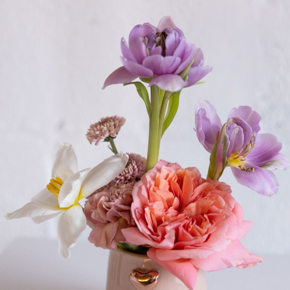 Bouquet of flowers including pink, purple, and white tulips with a white background