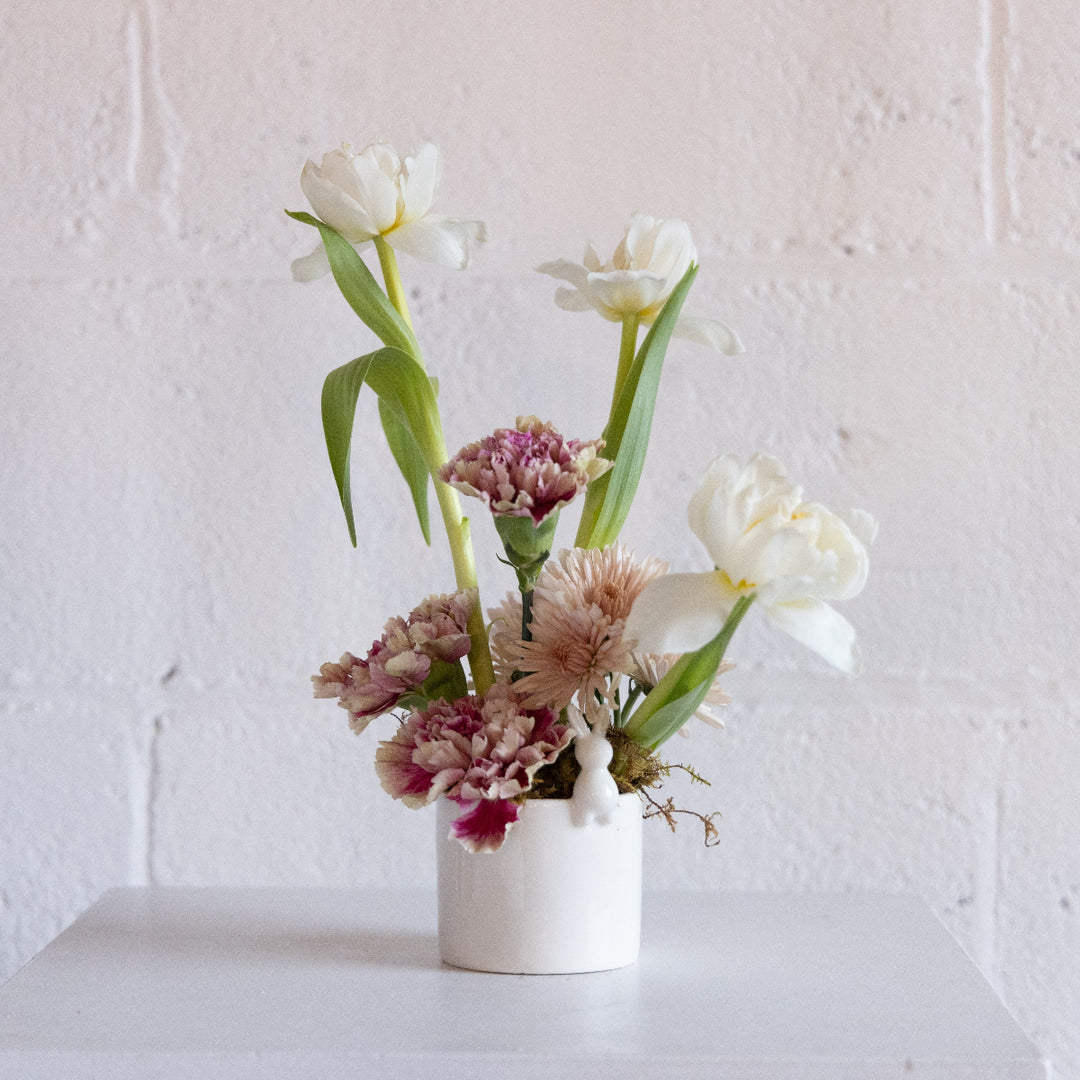 Floral arrangement in a white vase against a light pink wall