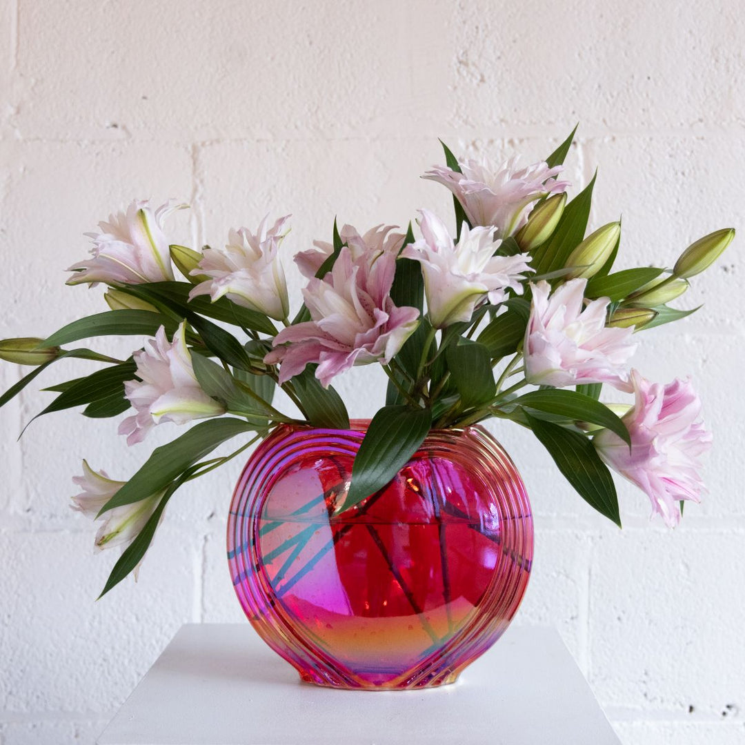 Multicolored glass vase with pink and white flowers on a white background