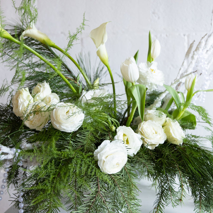 Floral arrangement with white flowers and greenery on a light background
