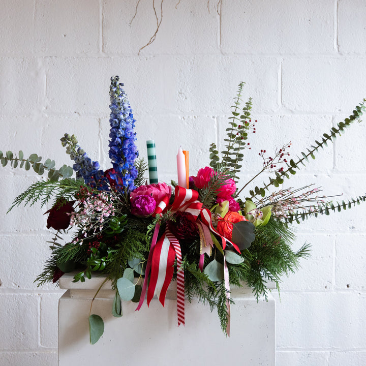 Colorful floral arrangement with ribbons and candles on a white brick wall background