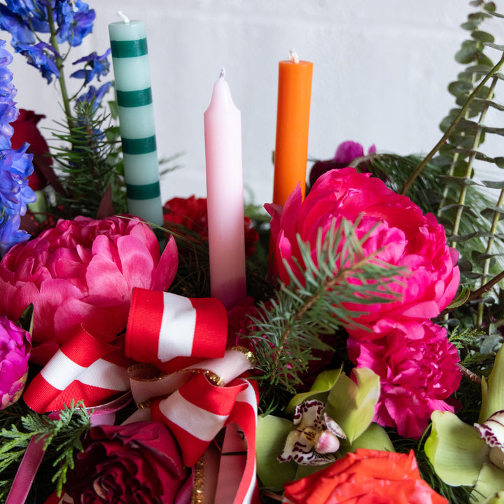 Decorative arrangement with flowers, candles, and ribbons on a white background