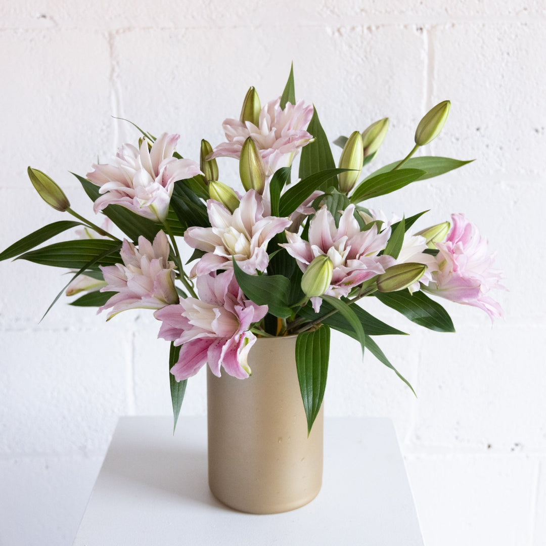 Gold vase full of Lily stems in pink