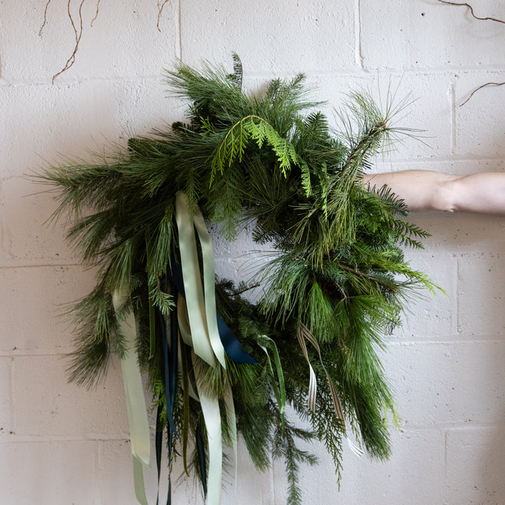 Green wreath with ribbons on a white brick wall