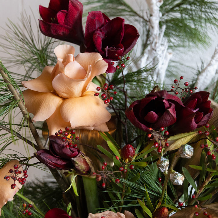 Close-up of a floral arrangement with red and pink flowers and green leaves.