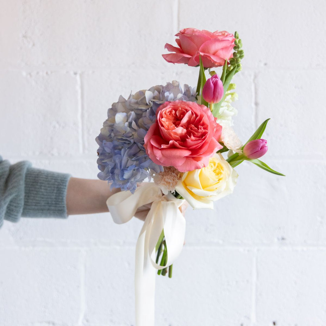 Bouquet of flowers held by a person against a white background