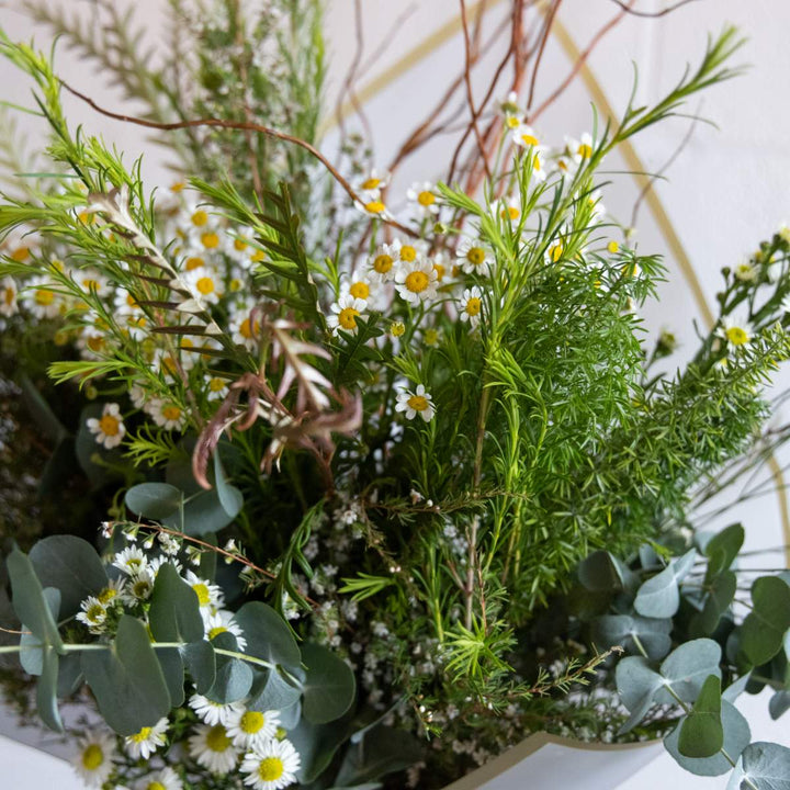 Close-up of a bouquet of greenery and small white flowers.