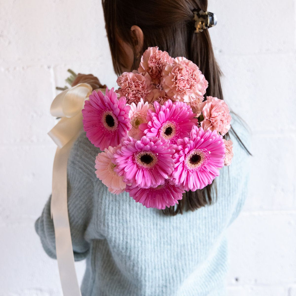 Person holding a bouquet of pink flowers with a white background