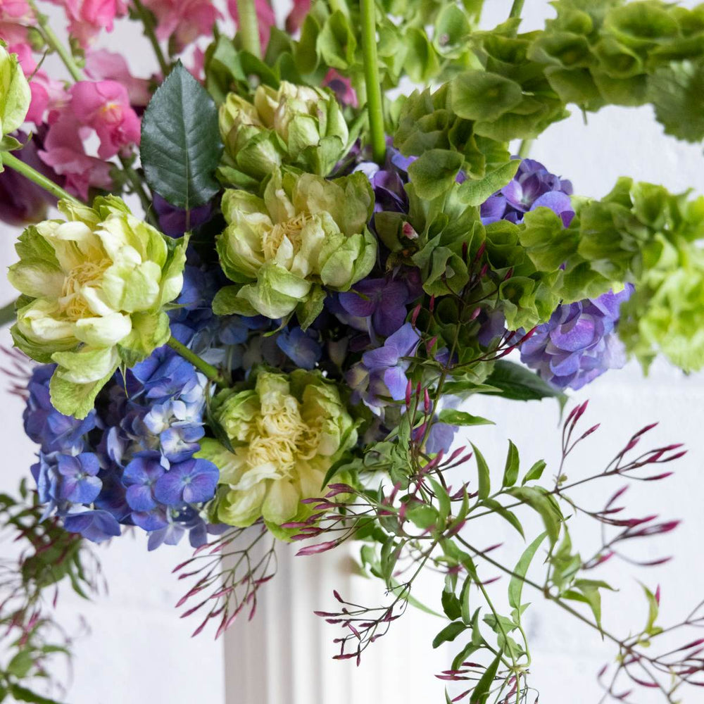 Bouquet of flowers with green, purple, and blue colors on a white background