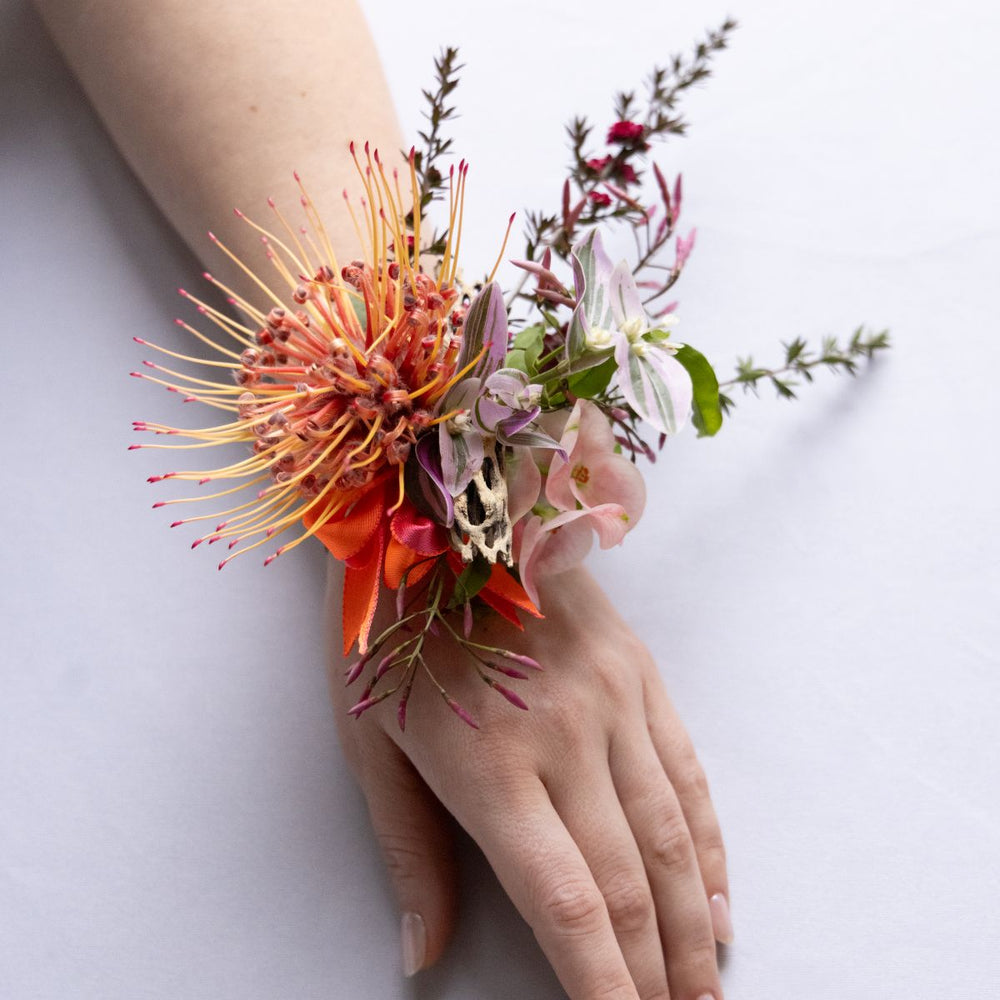 Floral wrist corsage on a person's wrist against a white background