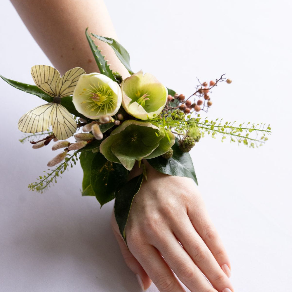 Wrist corsage with green flowers and butterflies on a white background