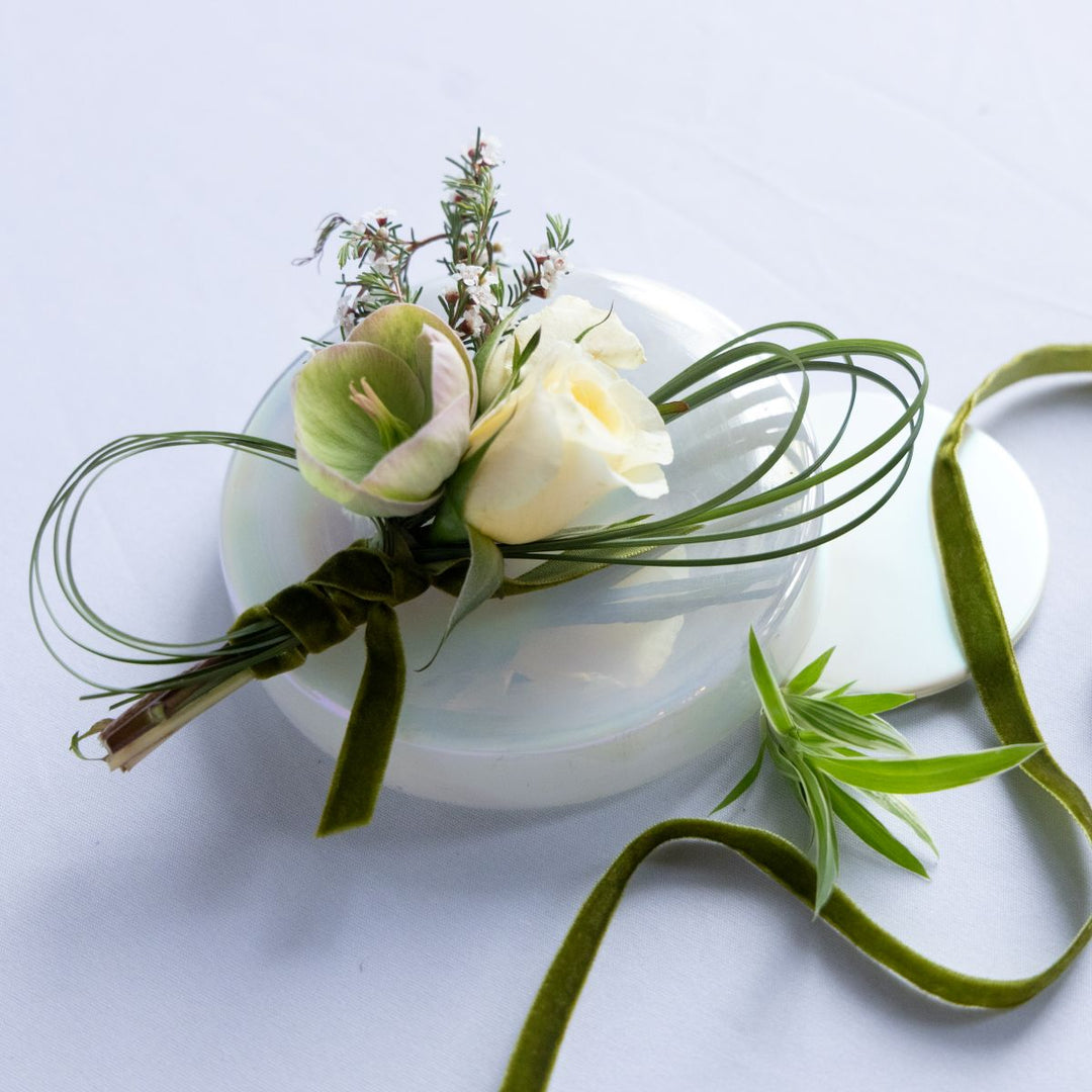 Floral boutonniere with green ribbon on a white background