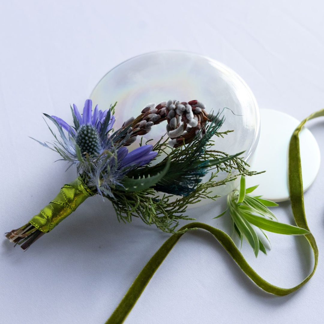 Floral boutonniere with green ribbon on a white background