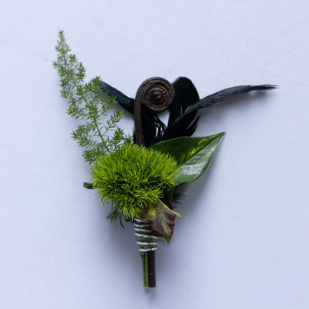 Green floral boutonniere with feathers on a white background