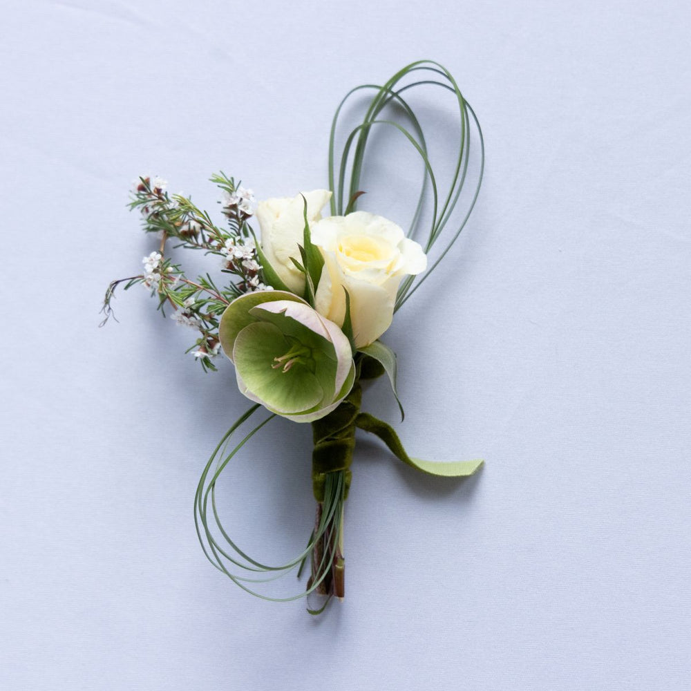 boutonniere with white roses and green leaves on a light background