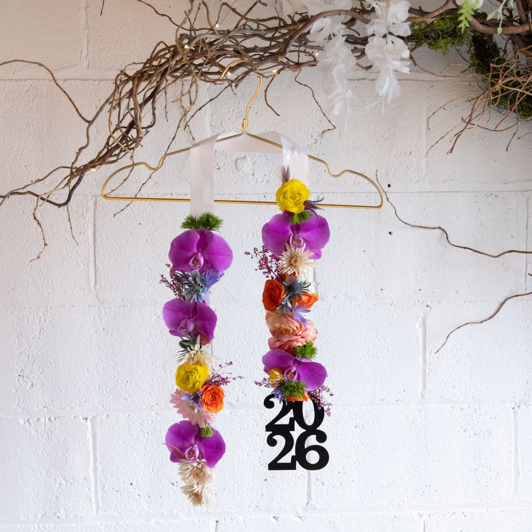 Colorful floral graduation stole on a hanger with a light background