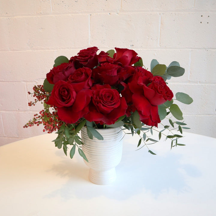 Dozen Roses Vased | This arrangement is in a white vase with one dozen red roses, eucalyptus greenery, on a white background.