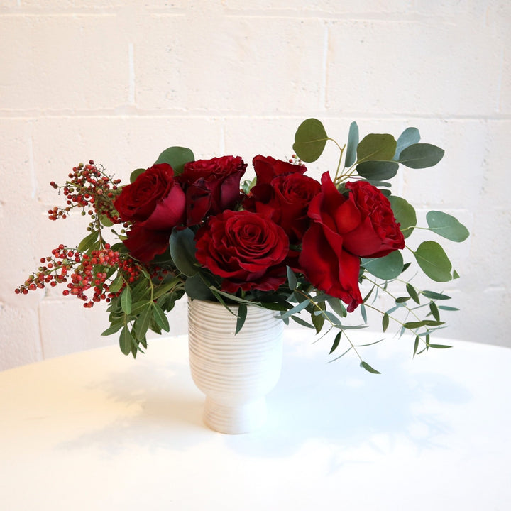 Half dozen red roses, with green eucalyptus and red pepper berry, taken on a white background.