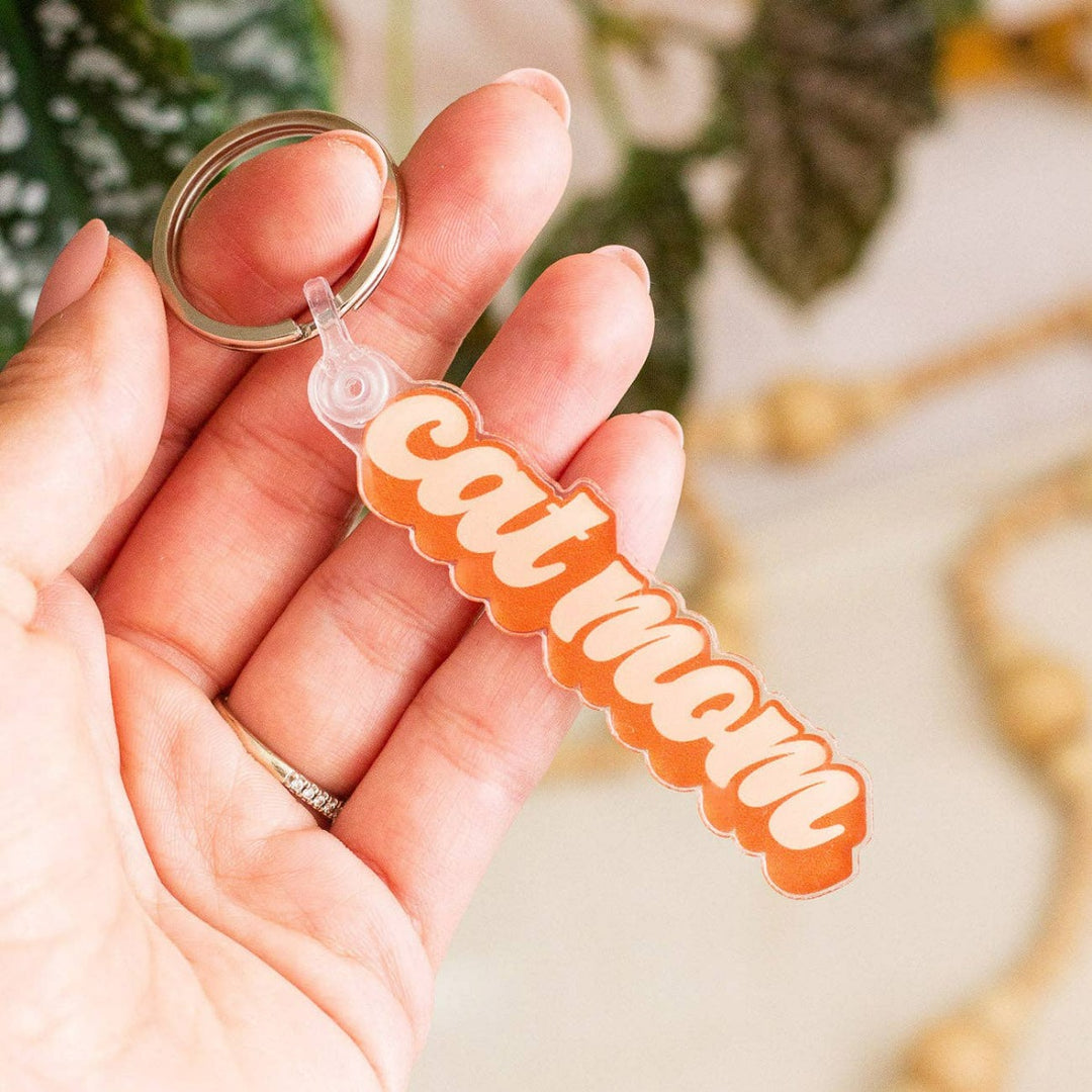 Keychains (Assorted Styles) | The Print Pantry | A keychain with the text "cat mom" in orange