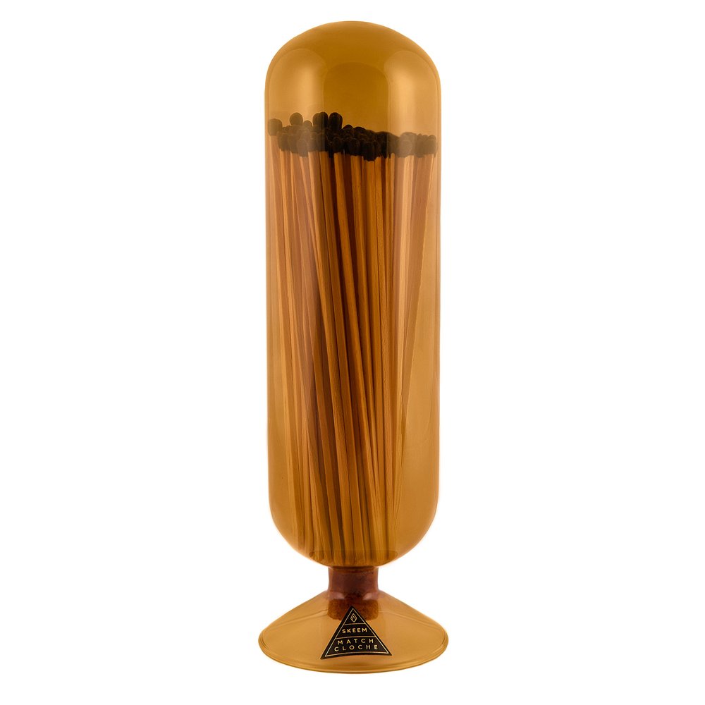 Skeem Amber Fireplace Match Cloche | Amber colored glass match cloche with fireplace matches inside. Photo taken against a white background.