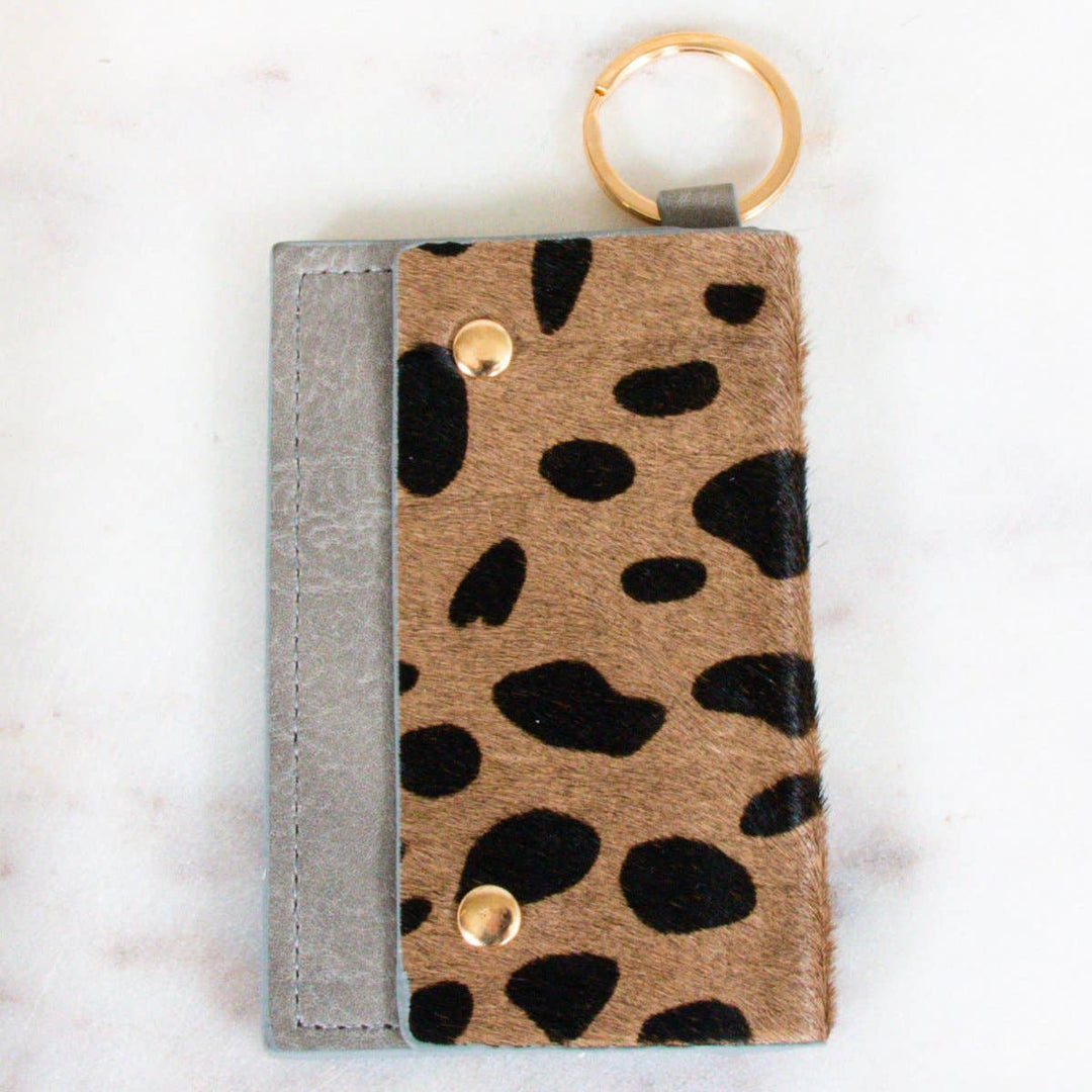 Caila Leather Cardholder W/ Snaps | A gray leather cardholder with a brown/black cow pattern and a gold key ring/snaps.