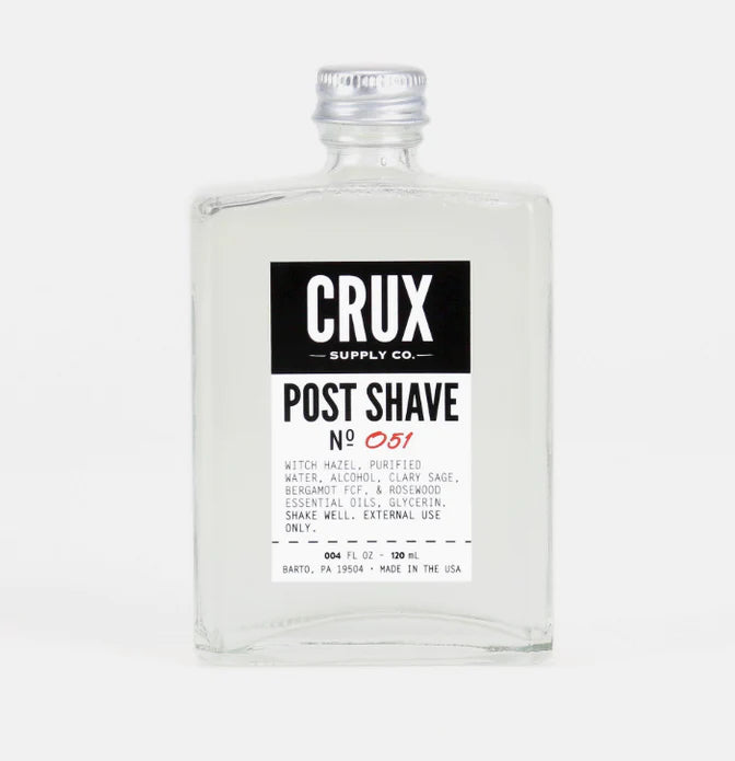 Crux Post Shave No 051 | Witch hazel, purified water, alcohol, clary sage, bergamot fcf, & rosewood essential oils, glycerin. Shake well. External use only. A clear glass bottle with a metal lid and a black and white label.
