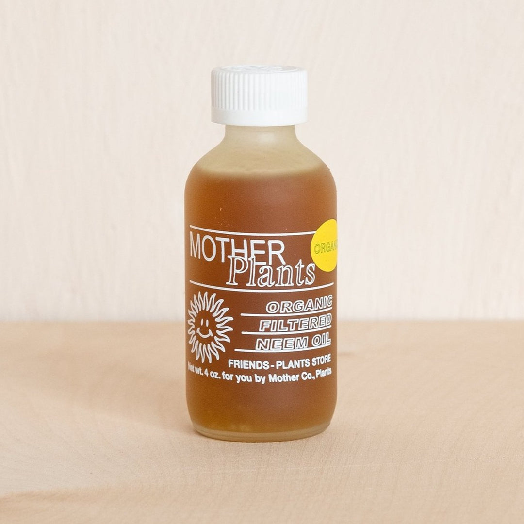 Organic Filtered Neem Oil | Mother Plants | A glass bottle with a white lid and white lettering.