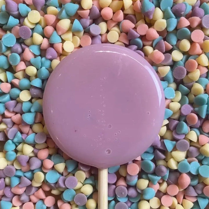 Good Lolli Unicorn Lollipop. Purple Lollipop with small multicolor vanilla chips placed devoratively in the background.
