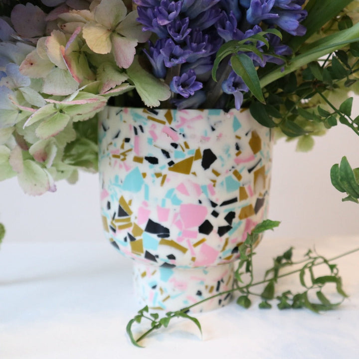 Close up of the white vase that has patches of pink, blue, gold, and black colors.