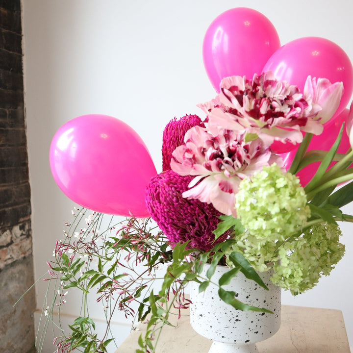 Cheerful | Close up on the balloons, pink, and green flowers.