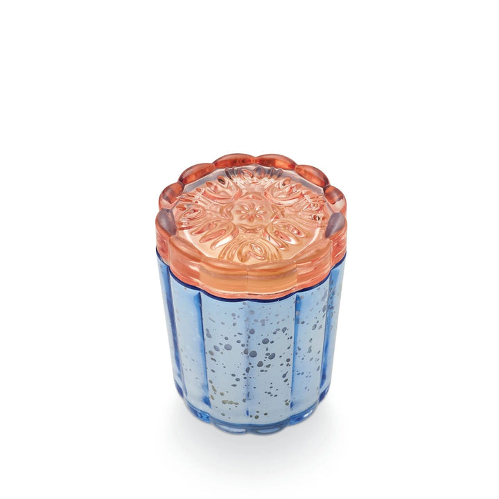Illume Citrus Crush Flourish Candle. Blue mercury glass with a pink glass floral pattern lid. Photo taken on a white background. Close up on the glass floral lid.
