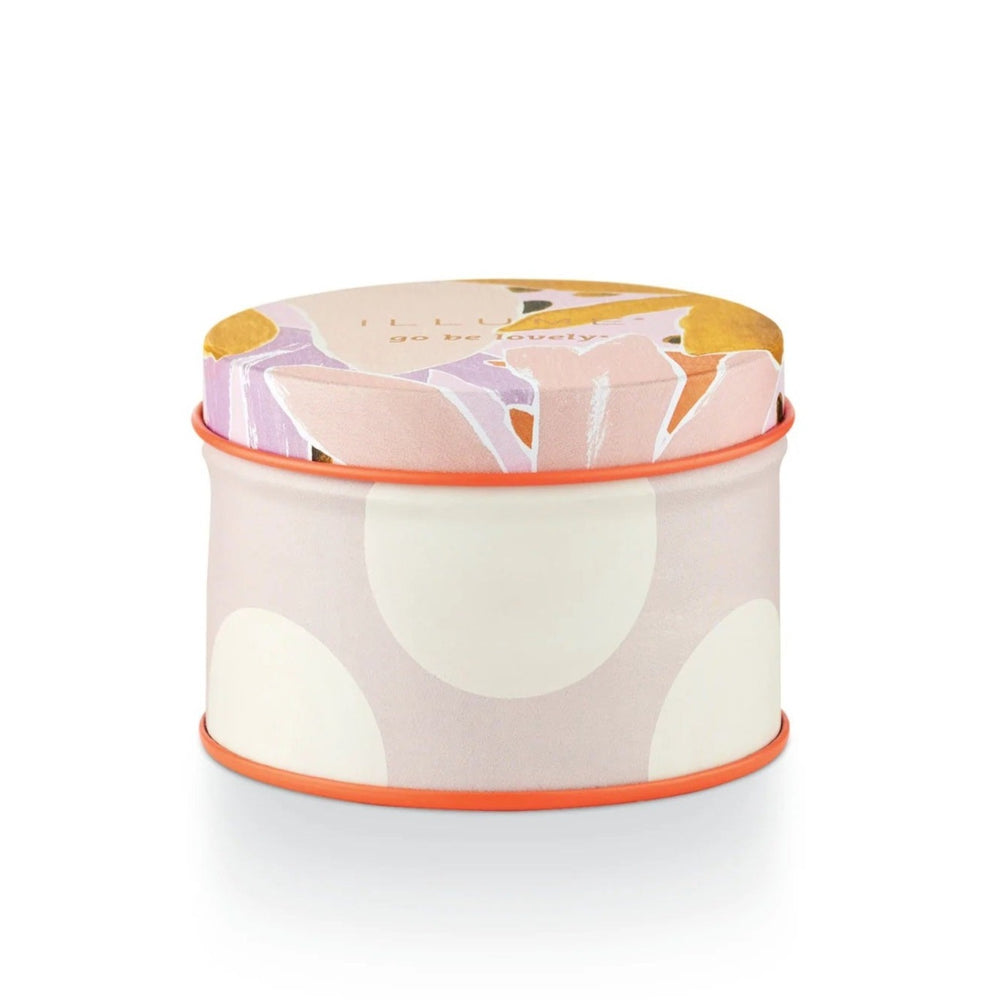 Illume Go Be lovely Lavender La La Fleur Tin Candle. A multi-color, pink, purple, yellow, orange, floral/polka dot candle. Photo taken on white background. Close up on the side of the tin.