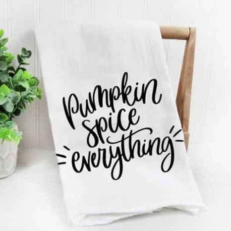 Festive Tea Towels | A white towel with black lettering "Pumpkin Spice everything". Towel is draped over a wooden dowel with a plant in the background.