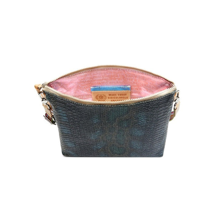 Rattler Downtown Crossbody | Consuela | A top down photo showcasing the pink textured interior with a pocket and the Consuela motto "Make Today Ridiculously Awesome!".
