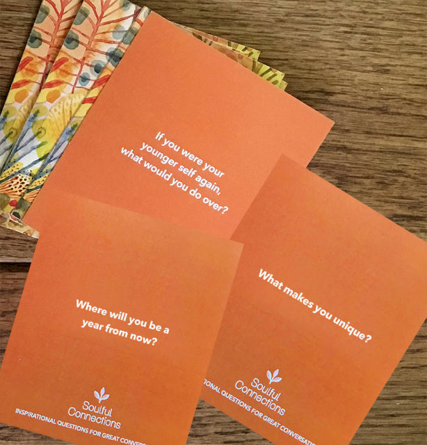 Soulful Connections | Peace and Pear | Up close photo of the cards. Orange with white text "If your were your younger self again, what would you do over?" "Where will you be a year from now?" "What makes you unique?".