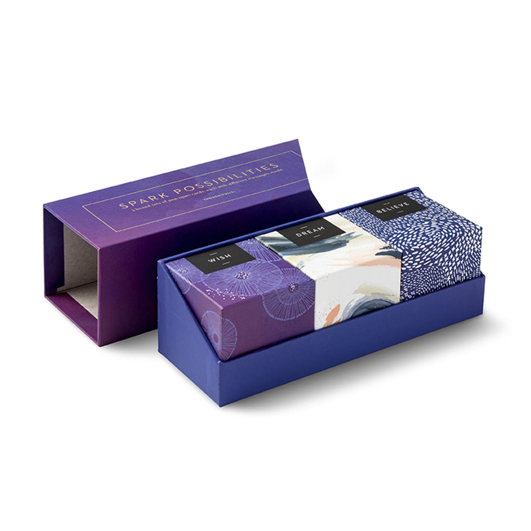 Spark Possibilities | Pop-Open Cards | Open box showing three smaller boxes on the inside. Wish, a purple box. Dream, a white box with blue, orange, and green brush strokes. Believe, a blue box with decorative white dash marks.