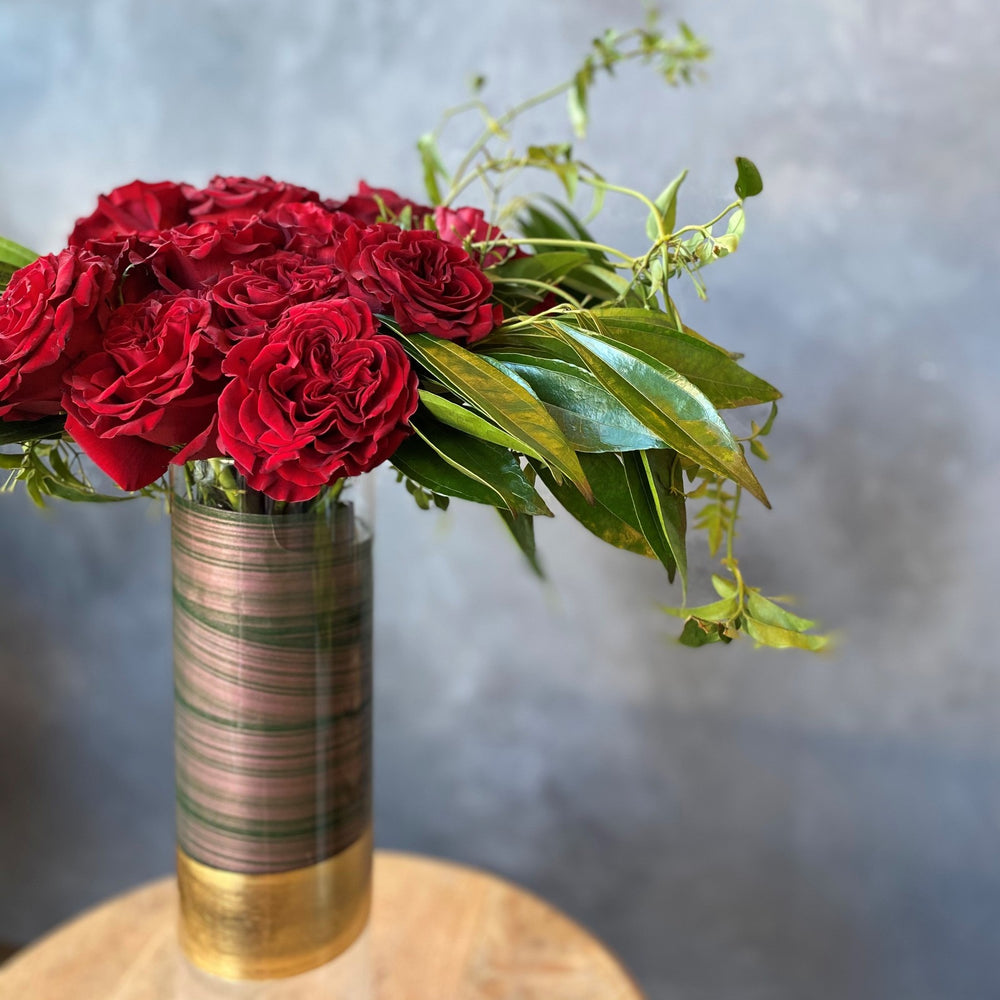 Dozen heart roses in glass vase with greenery