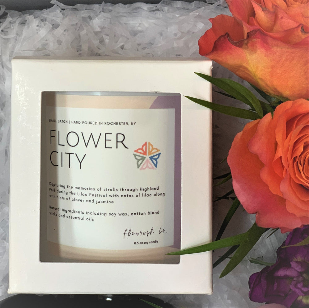 Close up of Fleurish Co. Flower City candle and fresh roses.