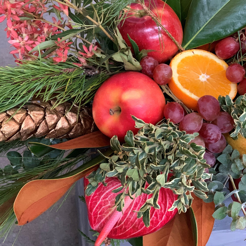 Close up of magnolia, apples, grapes, oranges, and greens.
