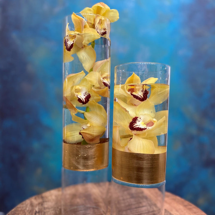 Yellow Cymbidium orchids in clear vase with gold band.