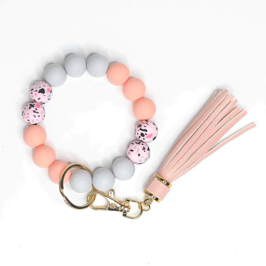 Assorted Beaded Keychains | A peach, gray, and pink speckled keychain bracelet with a good key ring and pink/gray tassel.